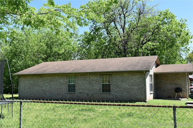 view of side of property with brick siding, a lawn, and fence