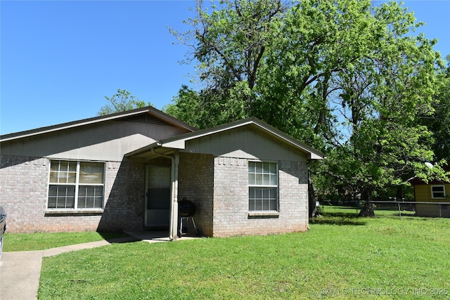 view of front of home featuring a front lawn, fence, and brick siding