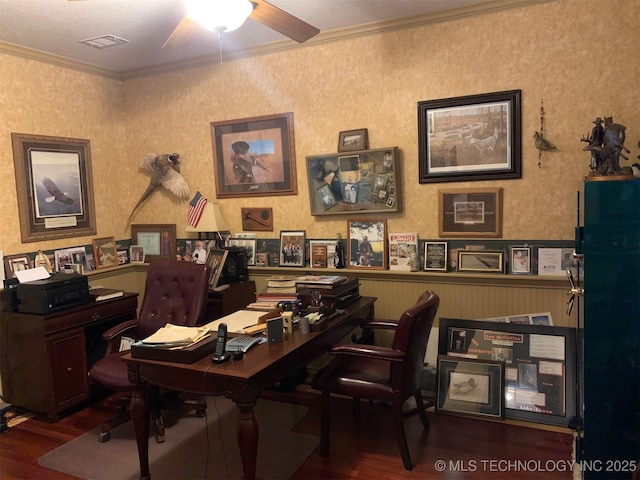 home office with a wainscoted wall, dark wood finished floors, visible vents, and crown molding