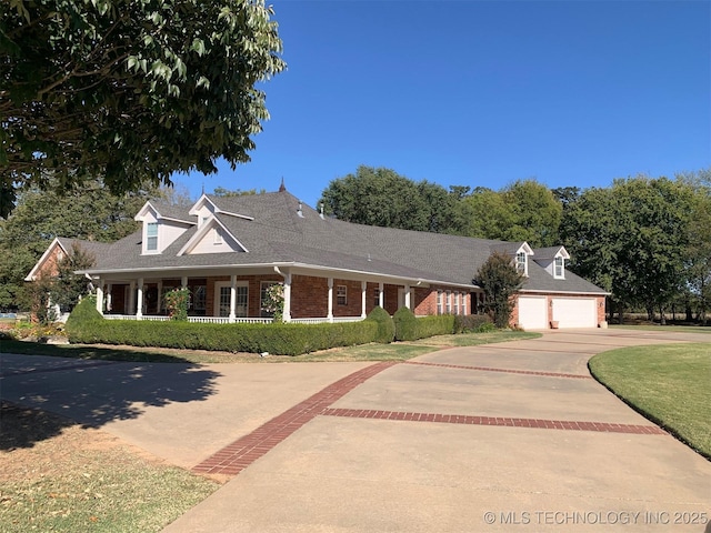 view of front of property featuring a front yard, covered porch, brick siding, and driveway