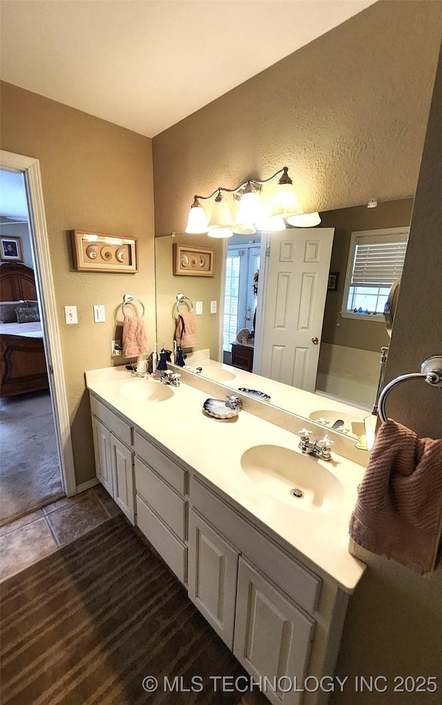 ensuite bathroom featuring ensuite bathroom, double vanity, and a sink