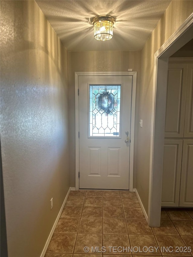 entryway with tile patterned floors, baseboards, and a textured ceiling