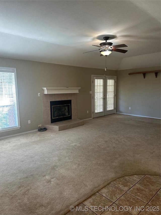 unfurnished living room with baseboards, a tile fireplace, a ceiling fan, and carpet