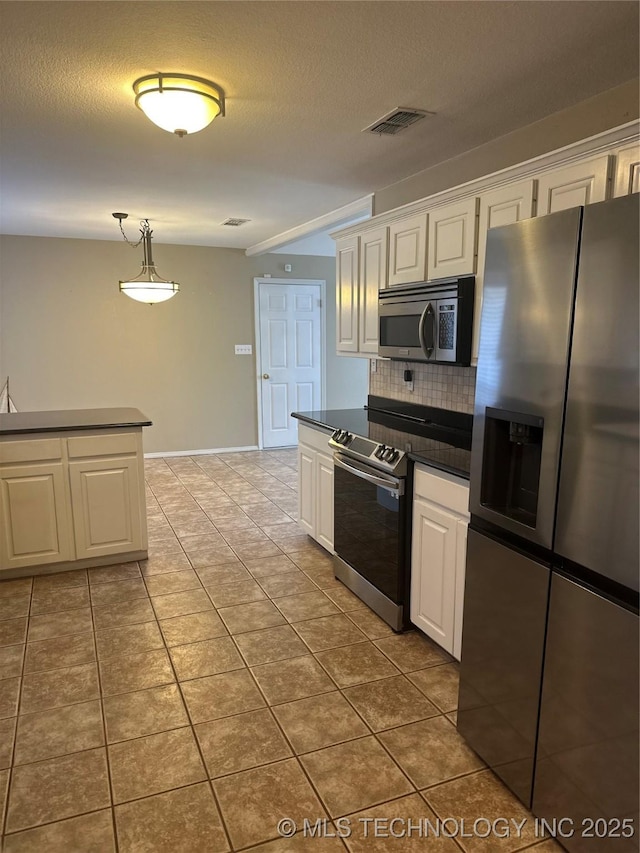 kitchen featuring visible vents, appliances with stainless steel finishes, white cabinetry, dark countertops, and backsplash