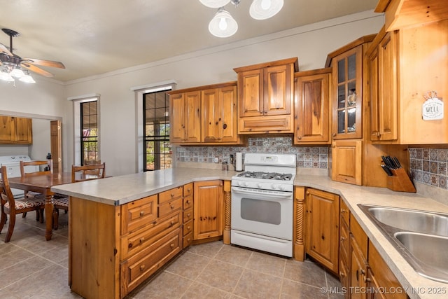 kitchen featuring white gas stove, a peninsula, light countertops, and glass insert cabinets