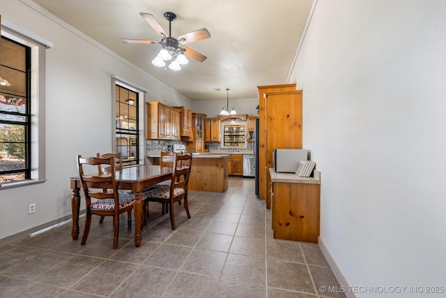 dining area featuring dark tile patterned floors, baseboards, ceiling fan, and crown molding