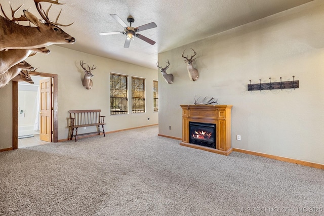 unfurnished living room with a glass covered fireplace, baseboards, a textured ceiling, and carpet