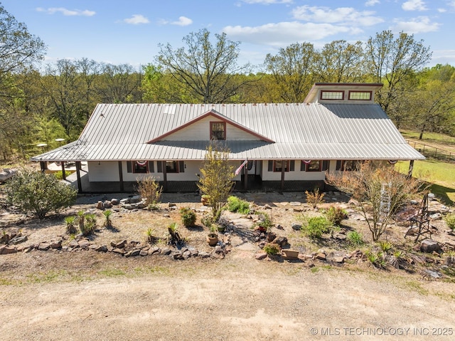 rear view of property with dirt driveway, metal roof, and a porch