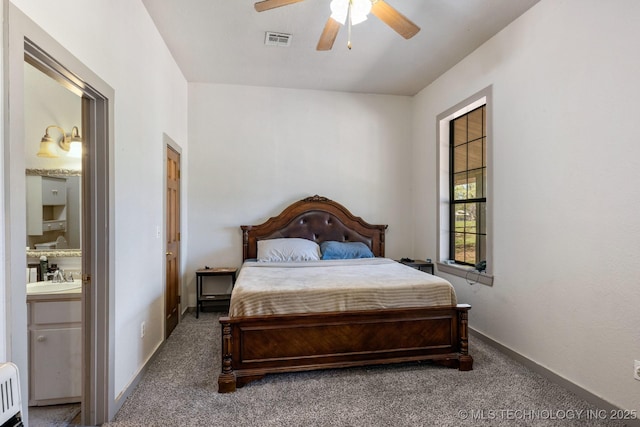 carpeted bedroom featuring ceiling fan, connected bathroom, a sink, visible vents, and baseboards