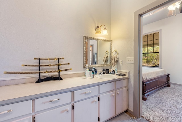 bathroom featuring a textured wall, vanity, baseboards, and ensuite bathroom