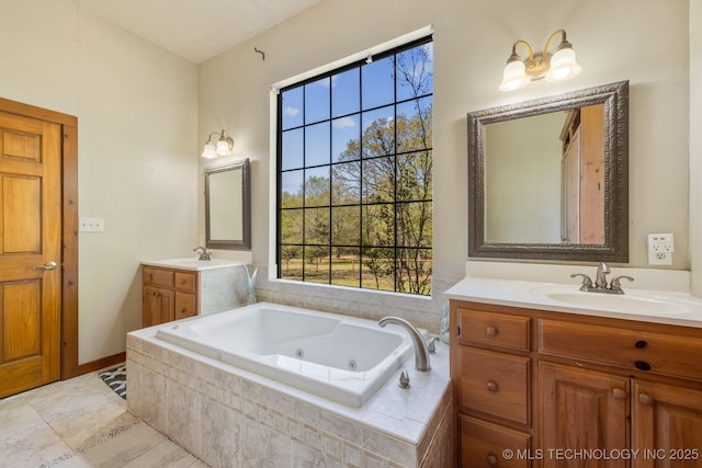 bathroom with a whirlpool tub, two vanities, a sink, and a wealth of natural light