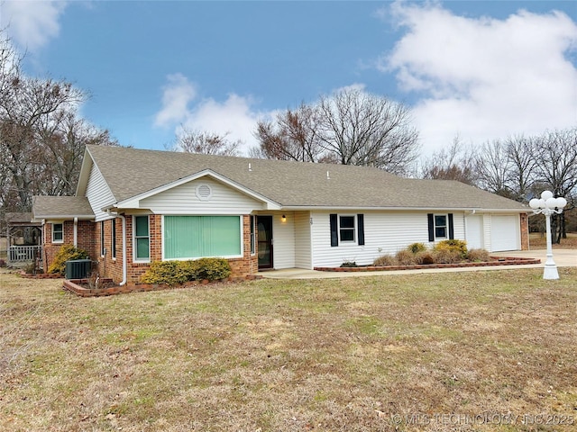 ranch-style home featuring cooling unit, brick siding, an attached garage, and a front yard