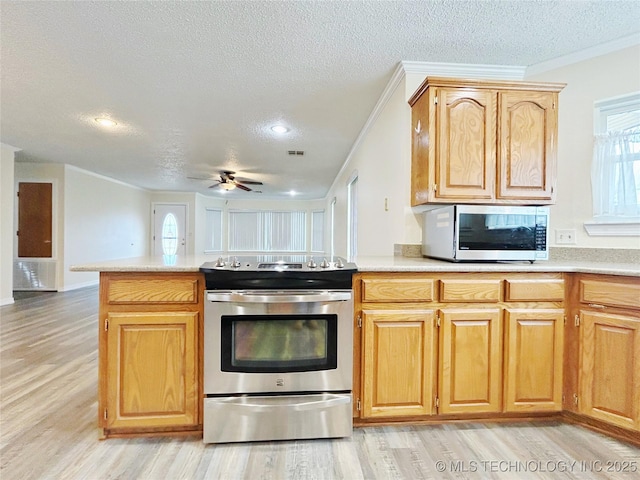 kitchen featuring light countertops, appliances with stainless steel finishes, a peninsula, and a healthy amount of sunlight