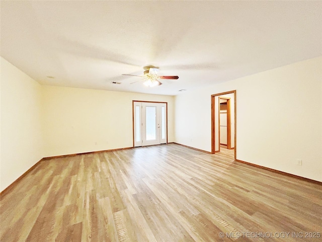 spare room with ceiling fan, light wood-style flooring, and baseboards