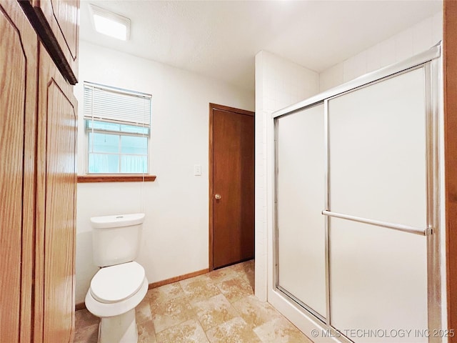 bathroom featuring toilet, a shower stall, and baseboards