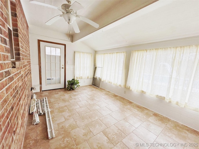 interior space featuring a ceiling fan, vaulted ceiling with beams, and brick wall