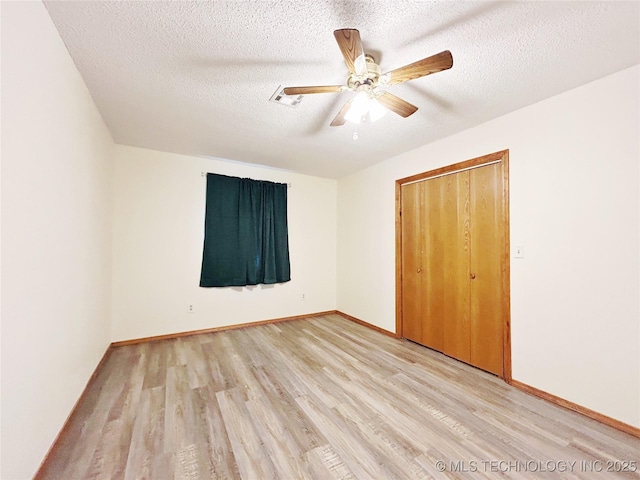 unfurnished bedroom with baseboards, a ceiling fan, light wood-style flooring, a textured ceiling, and a closet