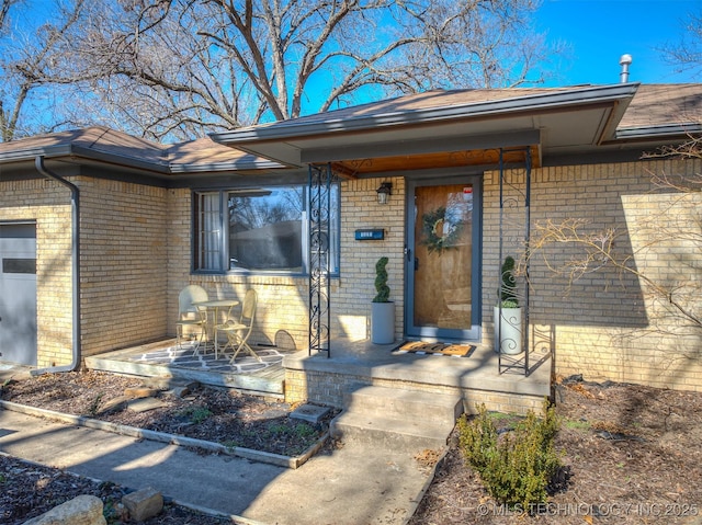 entrance to property with a garage and brick siding