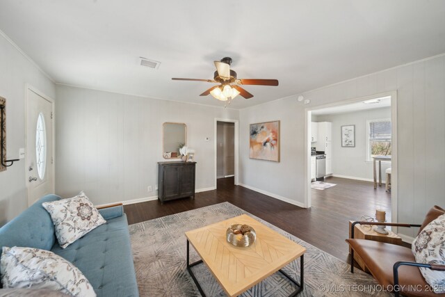 living room featuring baseboards, visible vents, a ceiling fan, and wood finished floors