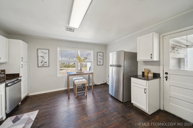 kitchen with appliances with stainless steel finishes, dark countertops, visible vents, and dark wood finished floors