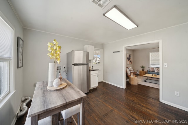 dining room featuring dark wood-style flooring, visible vents, crown molding, and baseboards