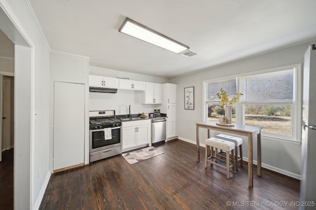 kitchen with under cabinet range hood, a sink, visible vents, appliances with stainless steel finishes, and dark wood finished floors