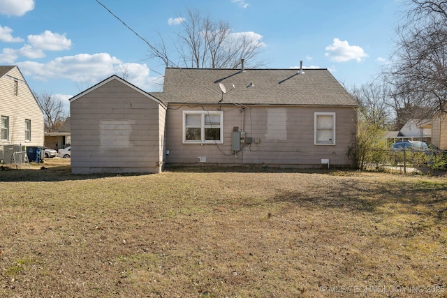 rear view of house featuring a yard, roof with shingles, and fence