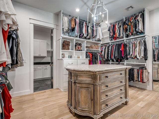 18420 E Persimmon Ln, Owasso, OK 74055 - walk in closet with light wood-type flooring and a chandelier