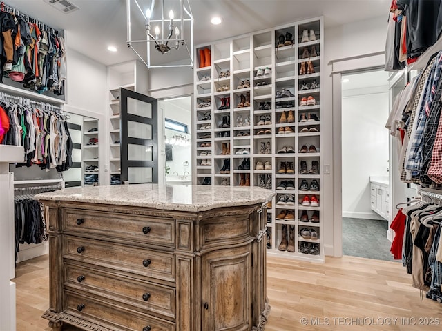 18420 E Persimmon Ln, Owasso, OK 74055 - walk in closet with light wood-style flooring and a chandelier