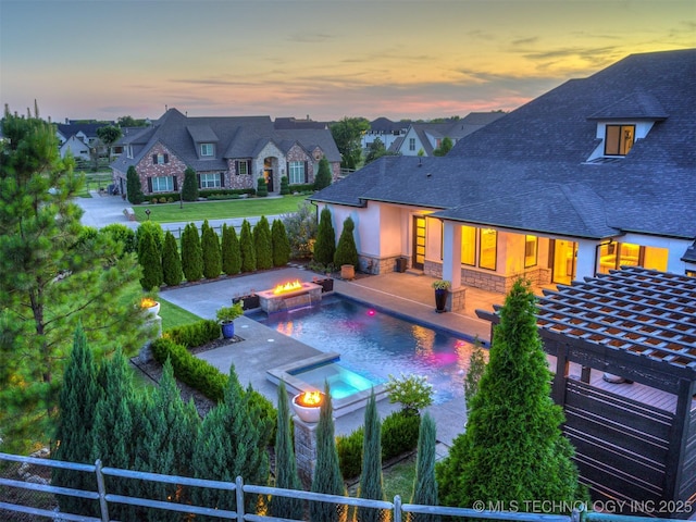 18420 E Persimmon Ln, Owasso, OK 74055 - back of property featuring a pool with connected hot tub, stone siding, a fenced backyard, and a patio area
