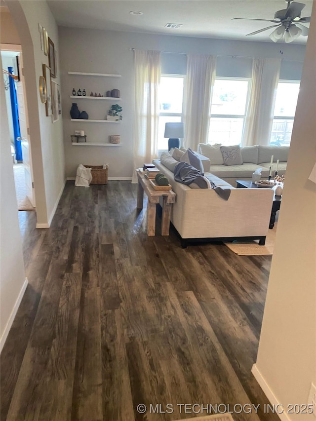 living room with visible vents, arched walkways, dark wood finished floors, baseboards, and ceiling fan