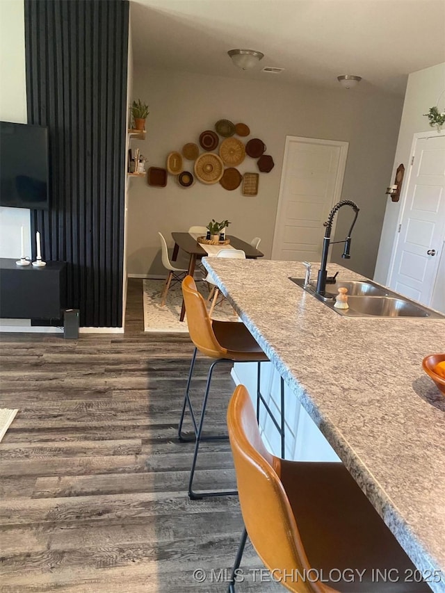 kitchen featuring dark wood-type flooring, a sink, visible vents, baseboards, and light countertops