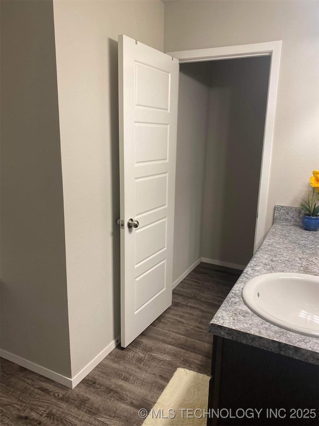 bathroom featuring baseboards, wood finished floors, and vanity