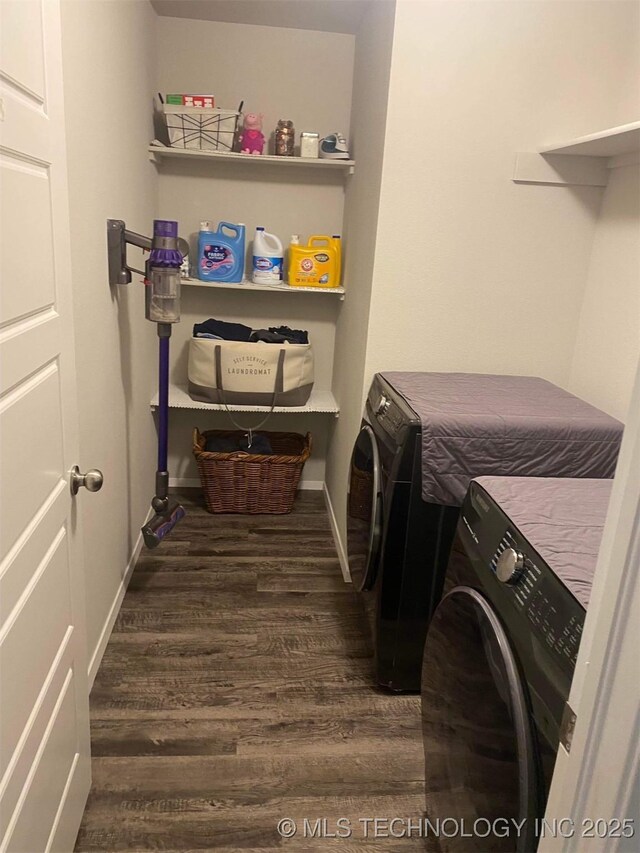 clothes washing area with laundry area, baseboards, dark wood-type flooring, and washer and dryer