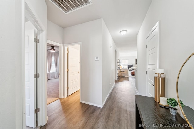 corridor with visible vents, baseboards, and wood finished floors