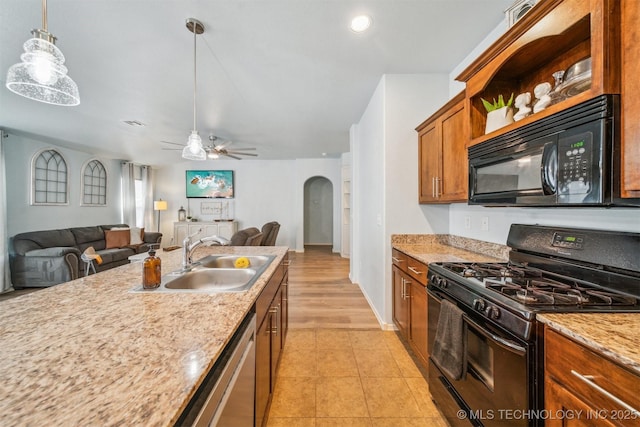 kitchen with arched walkways, brown cabinets, decorative light fixtures, a sink, and black appliances