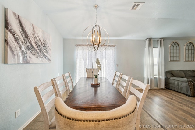 dining area with baseboards, visible vents, a chandelier, and wood finished floors