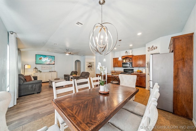 dining room featuring arched walkways, lofted ceiling, recessed lighting, visible vents, and ceiling fan with notable chandelier