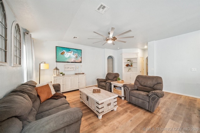 living area featuring arched walkways, ceiling fan, lofted ceiling, visible vents, and light wood-type flooring