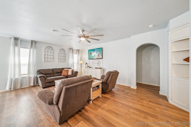 living room featuring arched walkways, plenty of natural light, light wood finished floors, and ceiling fan