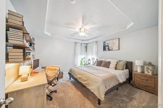 bedroom featuring a ceiling fan, a raised ceiling, light colored carpet, and a textured ceiling