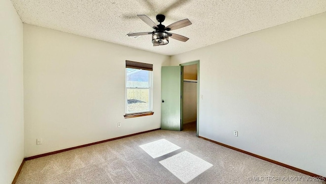 unfurnished bedroom with a closet, carpet flooring, ceiling fan, a textured ceiling, and baseboards