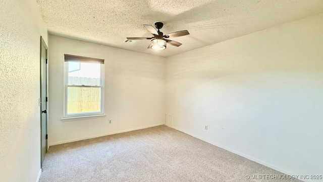 carpeted empty room with baseboards, visible vents, a ceiling fan, and a textured ceiling