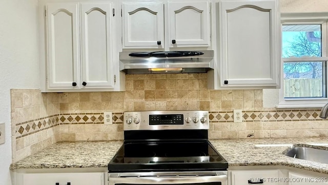 kitchen with tasteful backsplash, white cabinets, electric stove, light stone countertops, and under cabinet range hood