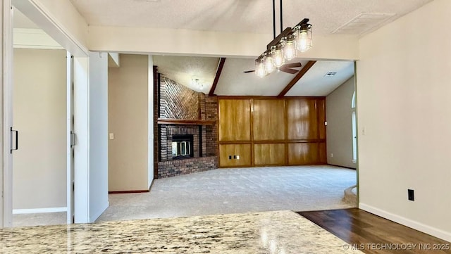 unfurnished living room with carpet floors, visible vents, baseboards, a brick fireplace, and beam ceiling