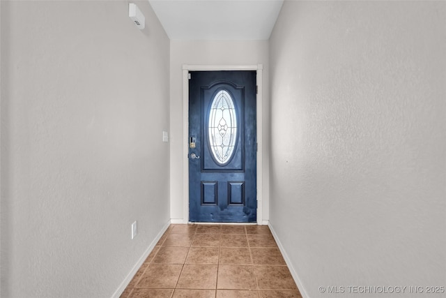 entryway featuring tile patterned flooring, a textured wall, and baseboards