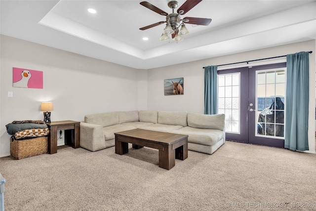 living room with french doors, a raised ceiling, light colored carpet, and recessed lighting