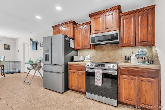 kitchen featuring appliances with stainless steel finishes, light countertops, decorative backsplash, and light tile patterned floors