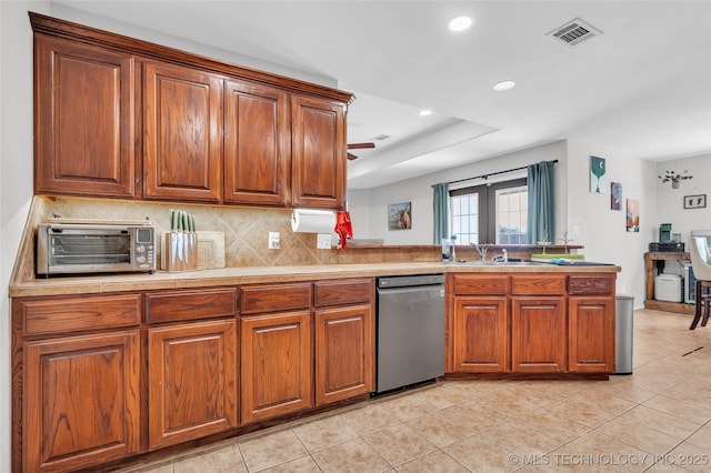 kitchen featuring brown cabinets, light countertops, visible vents, stainless steel dishwasher, and a sink