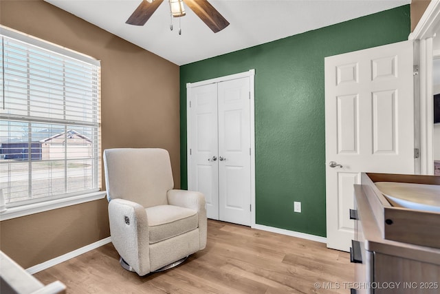 sitting room with a textured wall, baseboards, ceiling fan, and light wood finished floors